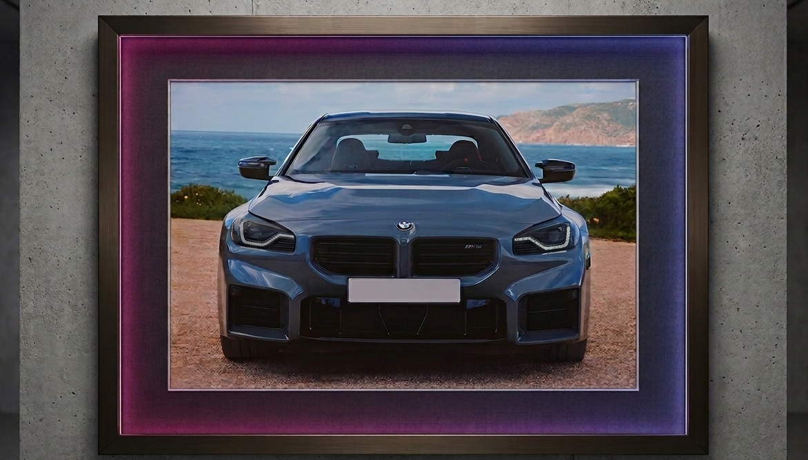 2x1.5 foot framed BMW M2 Coastal Journey car art print with built-in pink and blue LED frame lighting mounted on a modern concrete wall.